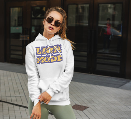 Woman wearing a white hoodie with 'LION PRIDE' text, standing on a sidewalk.